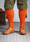 Long knitted shooting socks with a cable turnover in a bright orange nasturtium.