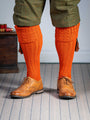 Long knitted shooting socks with a cable turnover in a bright orange nasturtium.