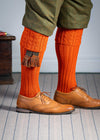 Long knitted shooting socks with a cable turnover in a bright orange nasturtium.