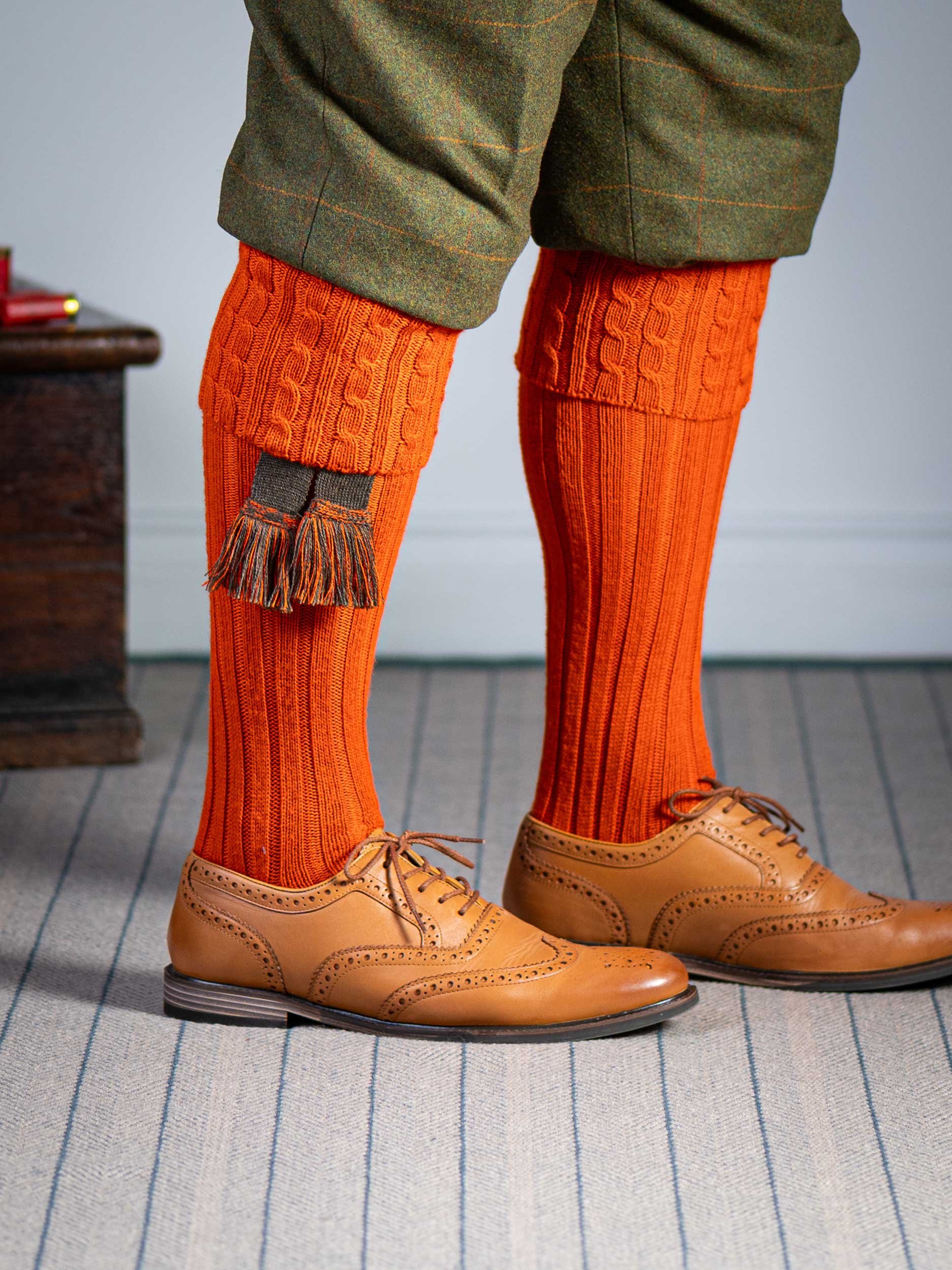 Long knitted shooting socks with a cable turnover in a bright orange nasturtium.