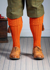 Long knitted shooting socks with a cable turnover in a bright orange nasturtium.