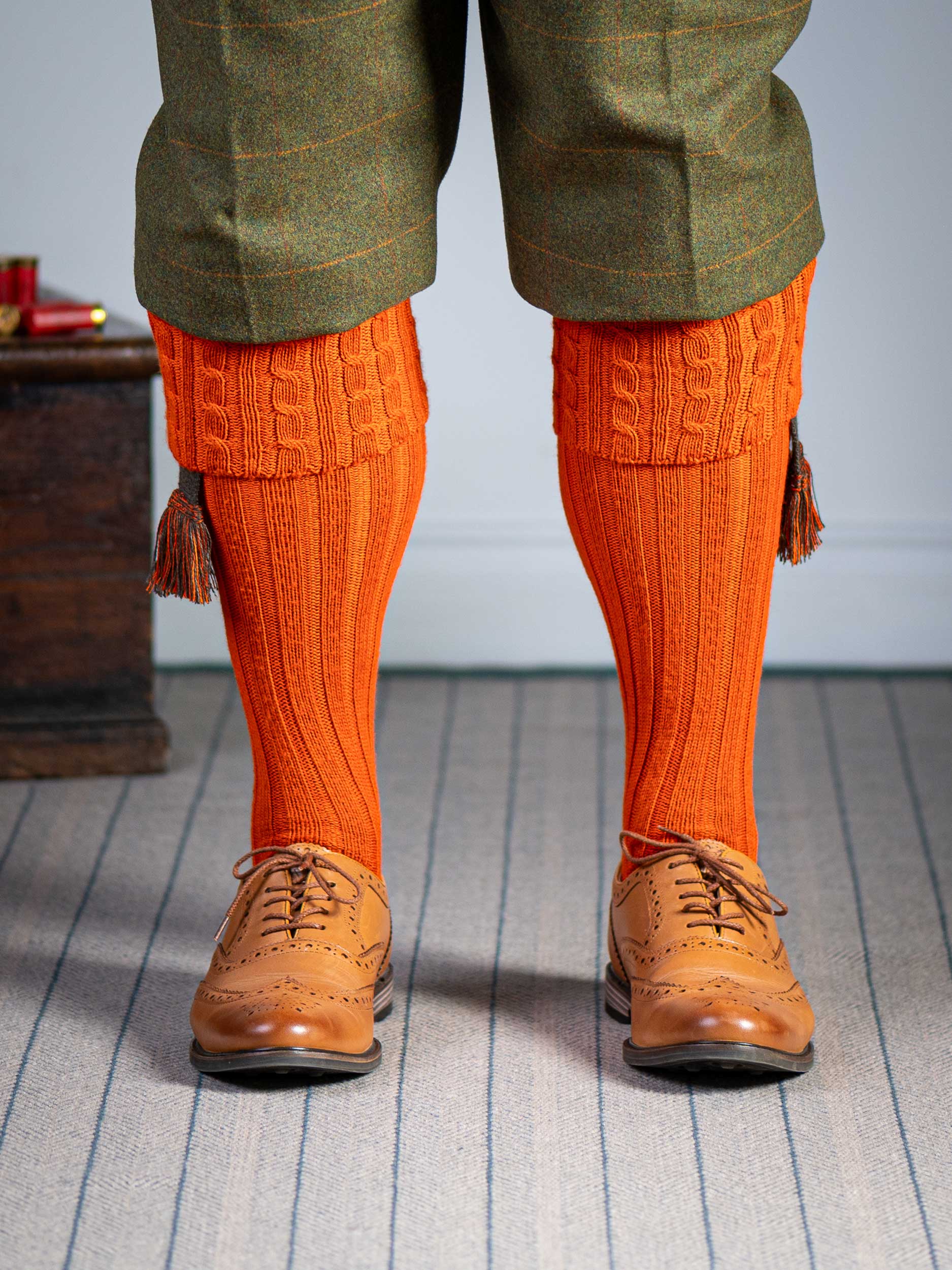 Long knitted shooting socks with a cable turnover in a bright orange nasturtium.