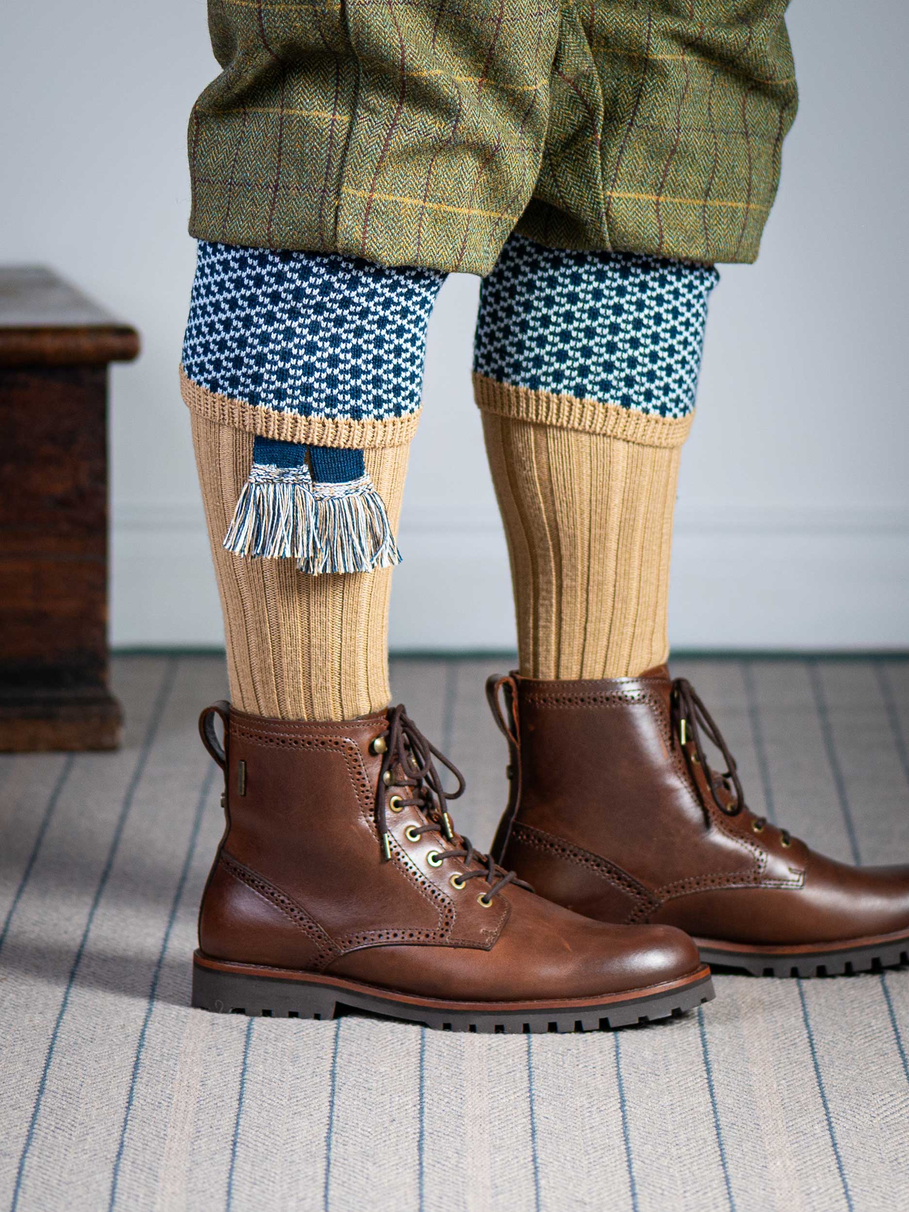 Long knitted shooting socks with a ribbed leg. Beige with a navy and sky blue pattern in the turnover top.