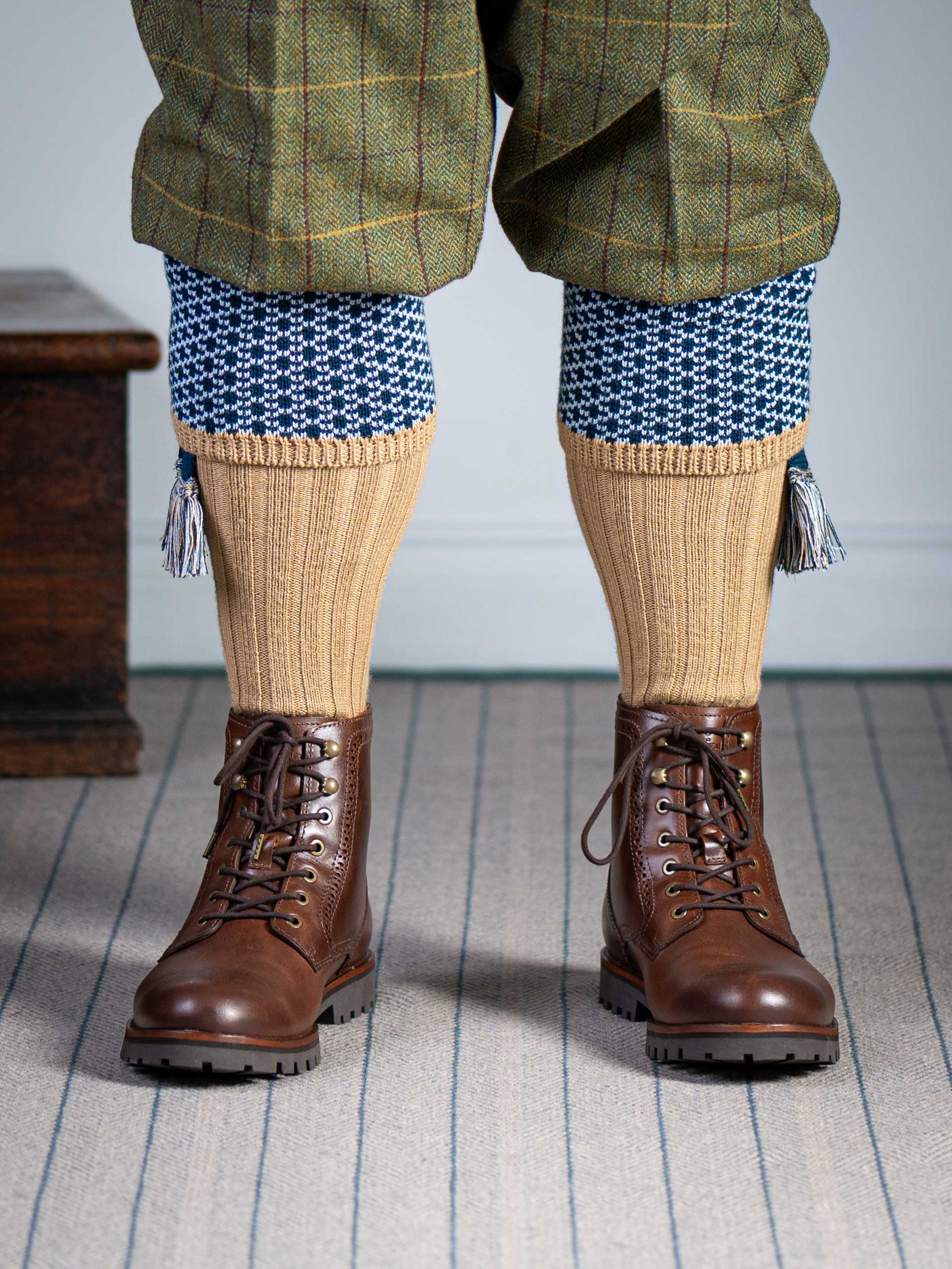 Long knitted shooting socks with a ribbed leg. Beige with a navy and sky blue pattern in the turnover top.