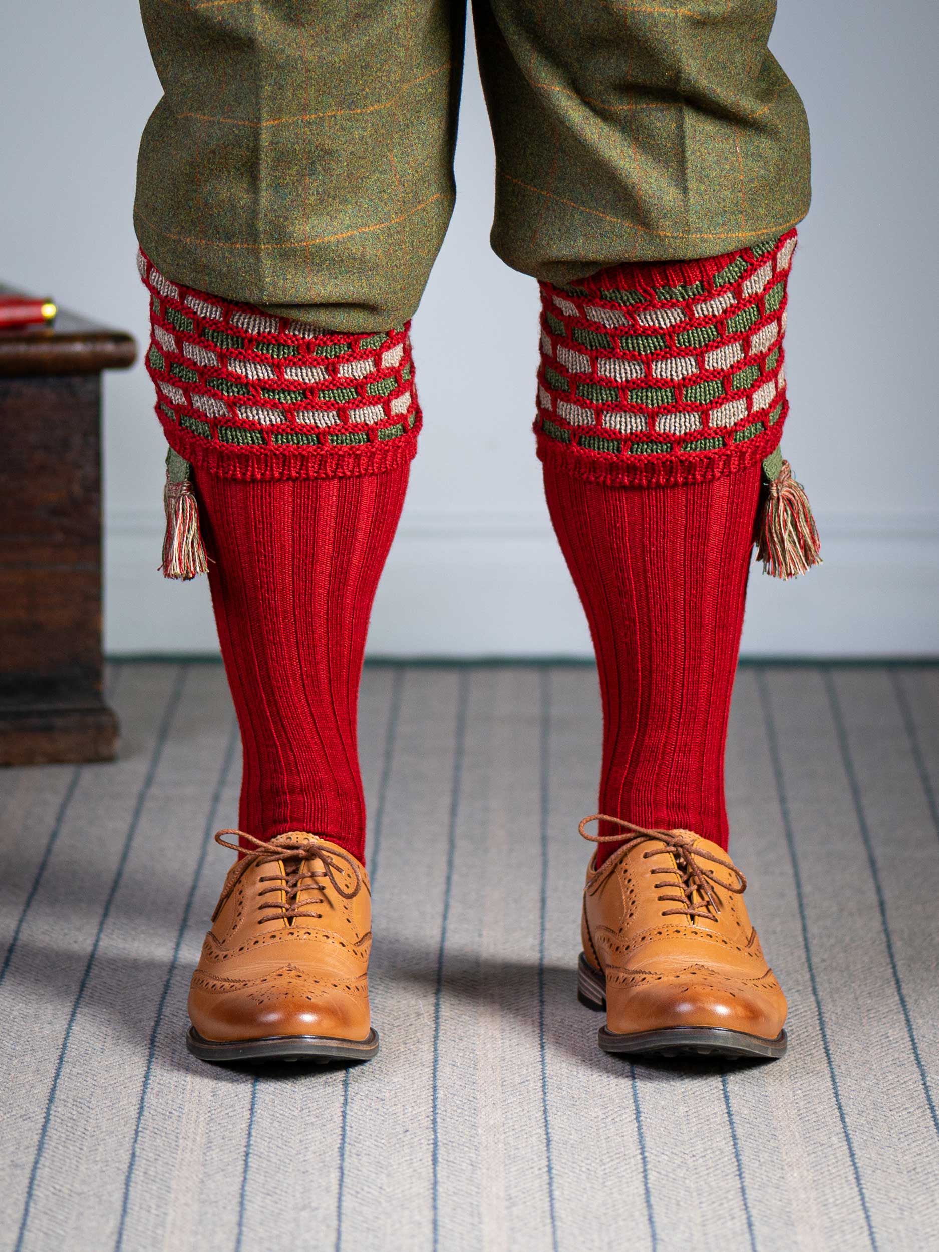 Traditional knitted shooting socks with a textured knitted top in brick red with green and beige pattern.