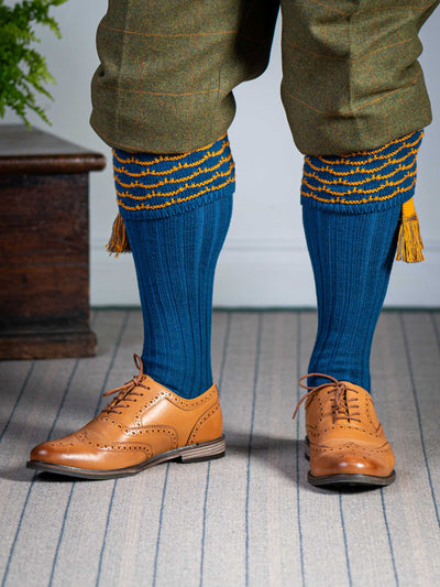 Traditional knitted shooting socks with ribbed leg in deep blue with a gold scallop stitch detail in the turnover top