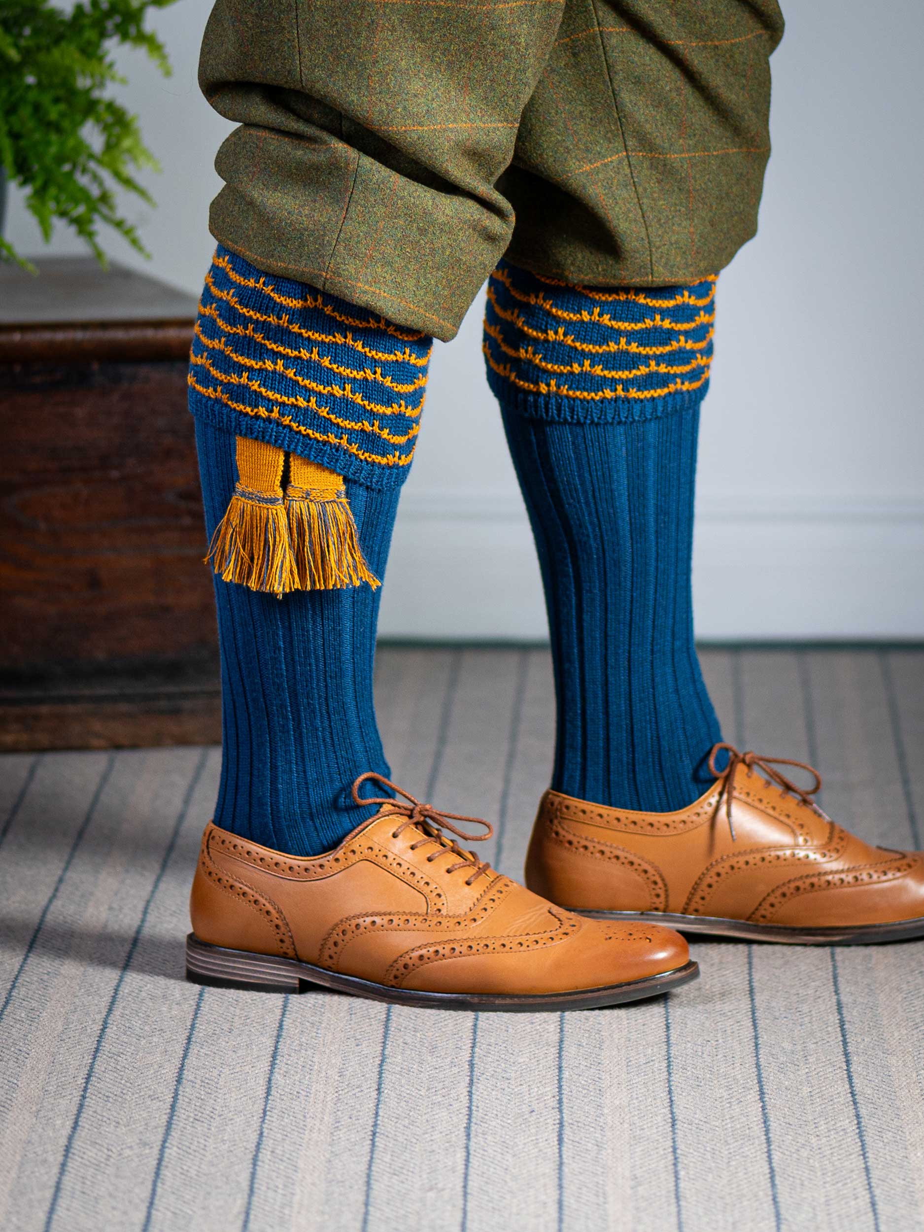 Traditional knitted shooting socks with ribbed leg in deep blue with a gold scallop stitch detail in the turnover top