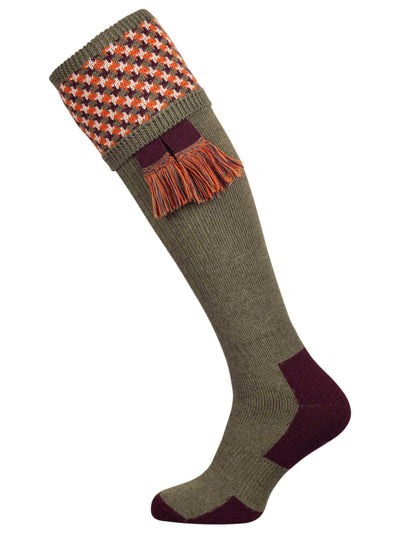 A contemporary technical shooting sock with supportive foot arch in dark olive with burgundy and orange pattern in the turnover