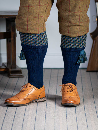 A contemporary technical shooting sock with supportive foot arch in navy blue with ancient blue and mulberry pattern in the turnover
