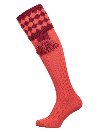 Salmon pink, knee high knitted sock with chessboard turnover and cherry red garter tie